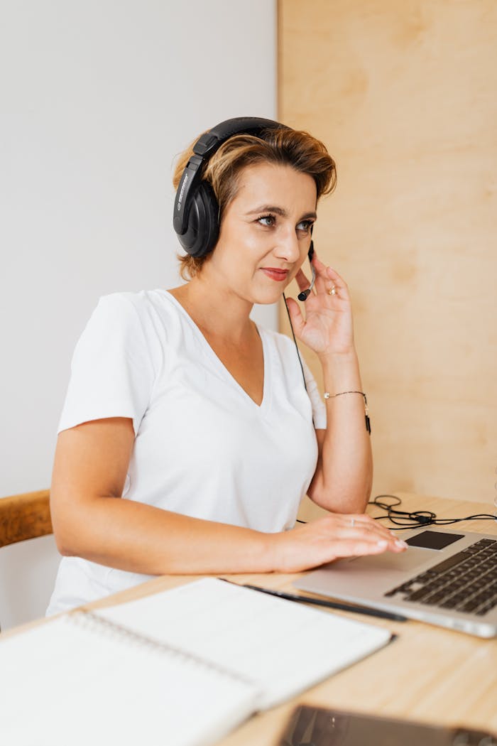 gallery-3 A woman in headphones works at a laptop in a modern office setting.